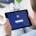 Mann hält ein iPad auf dem der Facebook Login-Bereich zu sehen ist