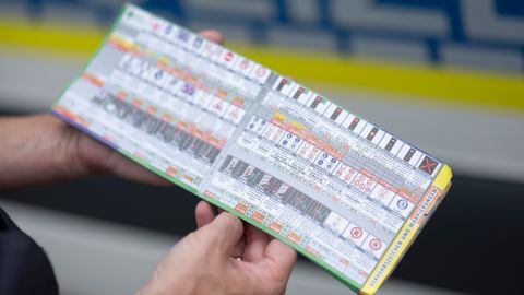 Two hands hold an open booklet with traffic signs and markings